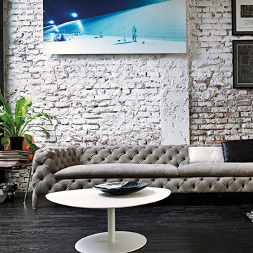 Modern minimalist painted brick wall with button back sofa and lacquered coffee