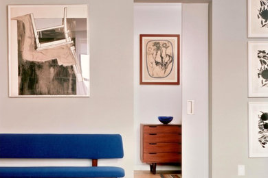 Diseño de salón abierto minimalista de tamaño medio con paredes grises y suelo de madera clara