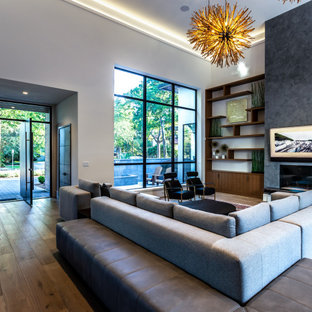 Foto di un ampio soggiorno moderno aperto con sala formale, parquet chiaro, camino bifacciale, cornice del camino in intonaco, TV a parete, pavimento marrone e soffitto ribassato