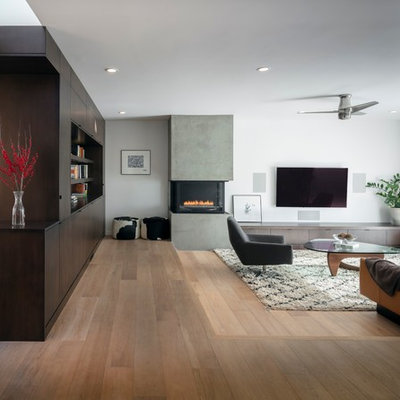 Inspiration for a large contemporary open concept light wood floor and brown floor living room remodel in San Francisco with white walls, a plaster fireplace, a wall-mounted tv and a two-sided fireplace