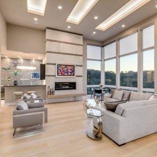 Offenes Modernes Wohnzimmer mit grauer Wandfarbe, hellem Holzboden, Gaskamin, beigem Boden und eingelassener Decke in Austin