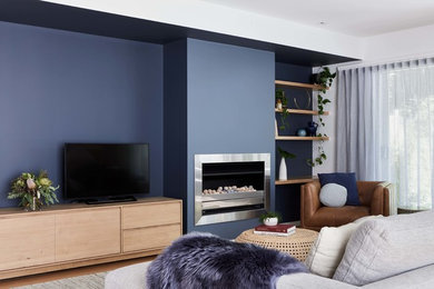Modelo de salón abierto escandinavo con paredes azules, suelo de madera clara y televisor independiente