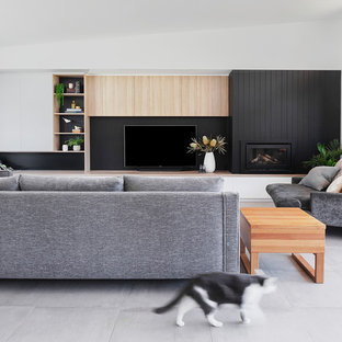 Esempio di un grande soggiorno minimal aperto con pareti bianche, pavimento con piastrelle in ceramica, cornice del camino in legno, TV a parete, pavimento grigio, sala formale e camino classico