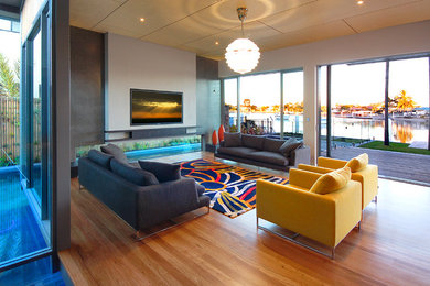 Großes, Repräsentatives, Offenes Eklektisches Wohnzimmer mit grauer Wandfarbe, braunem Holzboden, TV-Wand und braunem Boden in Sunshine Coast