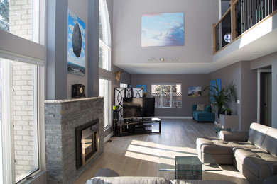 Großes Modernes Wohnzimmer im Loft-Stil mit grauer Wandfarbe, hellem Holzboden, Kamin, Kaminumrandung aus Stein und freistehendem TV in Toronto