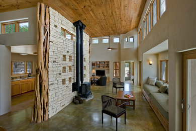 Diseño de salón abierto rural de tamaño medio con paredes beige, suelo de cemento, chimeneas suspendidas, marco de chimenea de piedra y suelo gris