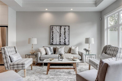 Modernes Wohnzimmer mit grauer Wandfarbe, hellem Holzboden und beigem Boden in Calgary