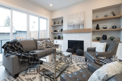 Offenes Rustikales Wohnzimmer mit beiger Wandfarbe, hellem Holzboden, Kamin, Kaminumrandung aus Holz und beigem Boden in Calgary