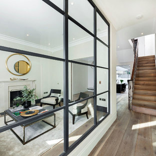 Modelo de salón clásico, grande, con paredes blancas y suelo de madera en tonos medios