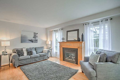 Transitional formal light wood floor and beige floor living room photo in Toronto with gray walls, a standard fireplace, a wood fireplace surround and no tv