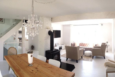 Diseño de salón abierto romántico de tamaño medio sin chimenea con paredes blancas, suelo de madera clara y televisor colgado en la pared
