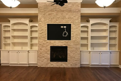 オレンジカウンティにあるトラディショナルスタイルのおしゃれなリビング (茶色い壁、無垢フローリング、標準型暖炉、石材の暖炉まわり、壁掛け型テレビ、茶色い床) の写真