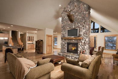 Large mountain style formal and open concept light wood floor and beige floor living room photo in Grand Rapids with beige walls, a two-sided fireplace, a stone fireplace and a wall-mounted tv