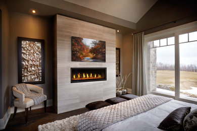 Example of a large trendy light wood floor and brown floor bedroom design in Omaha with beige walls and a standard fireplace