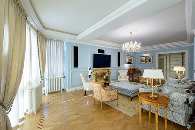 ノボシビルスクにあるラグジュアリーな広いトラディショナルスタイルのおしゃれなリビング (青い壁、淡色無垢フローリング、標準型暖炉、木材の暖炉まわり、壁掛け型テレビ) の写真