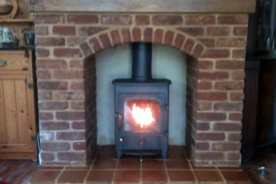 ハンプシャーにあるエクレクティックスタイルのおしゃれなリビング (薪ストーブ、レンガの暖炉まわり) の写真