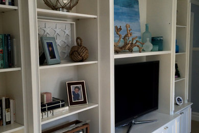 Example of a mid-sized beach style enclosed carpeted and beige floor living room design in New York with white walls, a media wall and no fireplace
