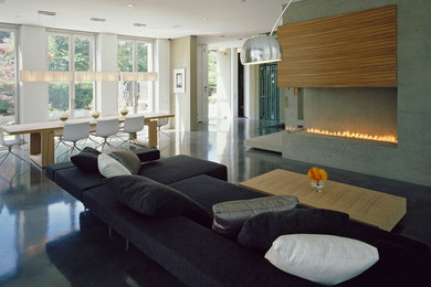 バンクーバーにあるコンテンポラリースタイルのおしゃれなリビング (コンクリートの暖炉まわり、黒いソファ) の写真