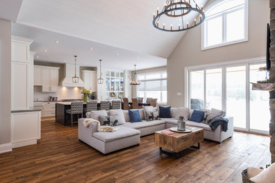 This is an example of an expansive traditional open plan living room in Toronto with grey walls, medium hardwood flooring, a stone fireplace surround, a wall mounted tv and brown floors.