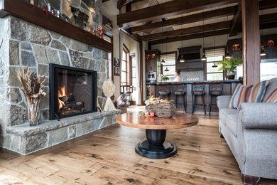 Example of a large mountain style open concept medium tone wood floor and brown floor living room design in Toronto with a standard fireplace and a stone fireplace