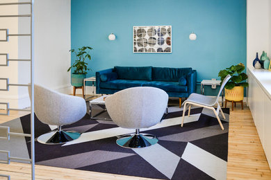 Foto de salón abierto retro de tamaño medio sin chimenea y televisor con paredes azules y suelo de madera clara