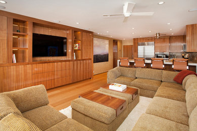 Modelo de salón abierto contemporáneo de tamaño medio sin chimenea con paredes beige, suelo de madera en tonos medios y pared multimedia