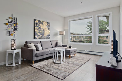 Skandinavisches Wohnzimmer mit grauer Wandfarbe, braunem Holzboden und freistehendem TV in Calgary