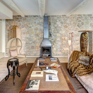 Exemple d'un grand salon avec une bibliothèque ou un coin lecture éclectique ouvert avec un mur beige, un sol en bois clair, une cheminée standard, un manteau de cheminée en métal et aucun téléviseur.