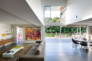 На фото: большая открытая гостиная комната в современном стиле с белыми стенами и телевизором на стене