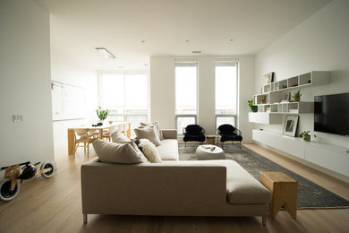 Imagen de salón abierto escandinavo con paredes blancas, suelo de madera clara, televisor colgado en la pared y suelo beige