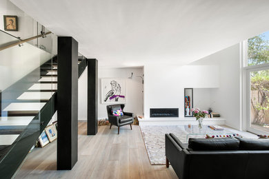 Idées déco pour un petit salon moderne ouvert avec un mur blanc, parquet clair, une cheminée standard et un manteau de cheminée en métal.
