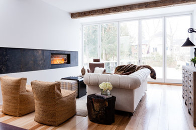 Cette image montre un salon design avec une salle de réception, un mur blanc, un sol en bois brun, une cheminée ribbon, un manteau de cheminée en carrelage et aucun téléviseur.