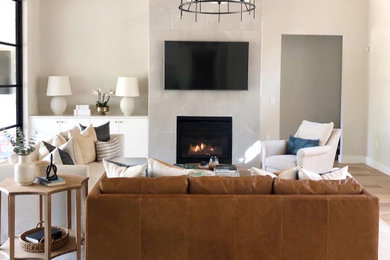Example of a transitional open concept medium tone wood floor and brown floor living room design in Austin with beige walls, a standard fireplace and a wall-mounted tv