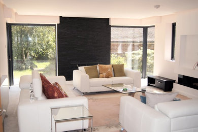 Mittelgroßes, Offenes Modernes Wohnzimmer mit weißer Wandfarbe, Teppichboden, Gaskamin, verputzter Kaminumrandung, Multimediawand und beigem Boden in Kent
