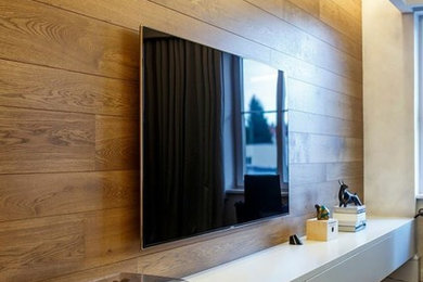 Bild på ett stort funkis allrum med öppen planlösning, med bruna väggar, mörkt trägolv och en väggmonterad TV