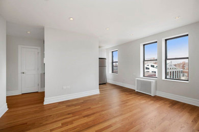 Mid-sized minimalist enclosed medium tone wood floor living room photo in New York with gray walls