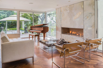 Example of a large minimalist formal medium tone wood floor living room design in Los Angeles with a ribbon fireplace and a stone fireplace