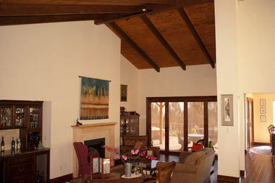 Imagen de salón con barra de bar abierto tradicional de tamaño medio con paredes beige, suelo de madera oscura y suelo marrón