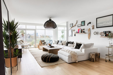 Imagen de salón abierto contemporáneo de tamaño medio sin chimenea con paredes blancas, suelo de madera clara, televisor colgado en la pared y suelo marrón