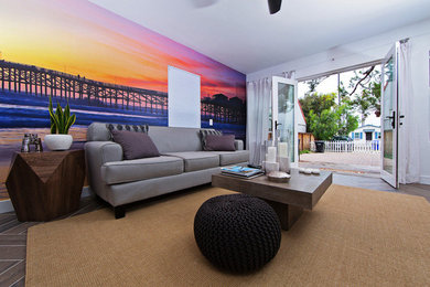 サンディエゴにある中くらいなビーチスタイルのおしゃれな独立型リビング (白い壁、磁器タイルの床、標準型暖炉、石材の暖炉まわり、壁掛け型テレビ、茶色い床) の写真
