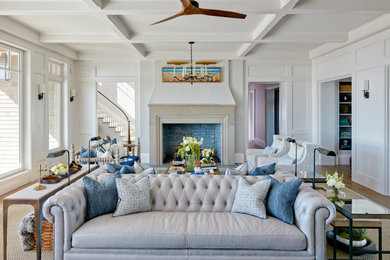 Example of a large beach style medium tone wood floor living room design in Charleston with white walls, a standard fireplace and a stone fireplace