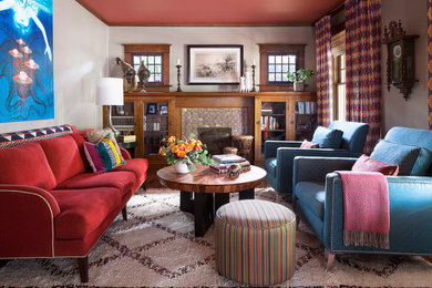 デンバーにあるエクレクティックスタイルのおしゃれなリビング (グレーの壁、無垢フローリング、標準型暖炉、タイルの暖炉まわり、茶色い床、赤いソファ) の写真