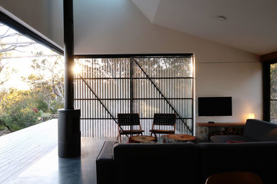 Источник вдохновения для домашнего уюта: маленькая открытая гостиная комната в стиле модернизм с белыми стенами, бетонным полом, стандартным камином, фасадом камина из металла и черным полом для на участке и в саду