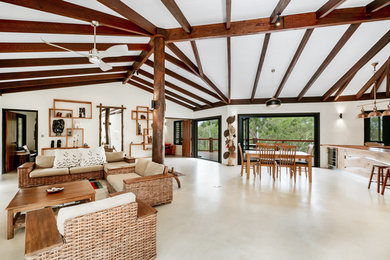 Mittelgroßes, Offenes Uriges Wohnzimmer mit weißer Wandfarbe, Betonboden, Kaminofen und TV-Wand in Cairns