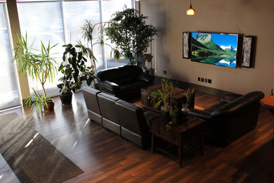 Modelo de salón abierto tradicional grande sin chimenea con paredes beige, suelo de madera en tonos medios y televisor colgado en la pared