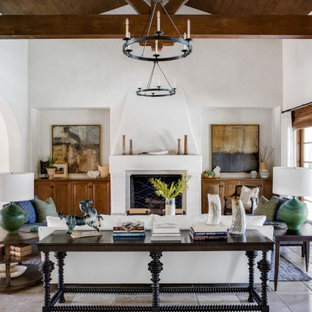 This is an example of a large mediterranean formal open plan living room in Orange County with white walls, travertine flooring, a standard fireplace, a plastered fireplace surround, no tv and beige floors.