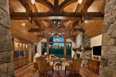 Example of a large mountain style formal and enclosed dark wood floor living room design in Sacramento with white walls, a standard fireplace, a stone fireplace and a wall-mounted tv