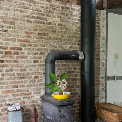 Example of a mid-sized farmhouse enclosed brick floor living room design in New York with a wood stove and a brick fireplace