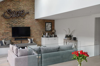 Ejemplo de salón abierto contemporáneo pequeño con paredes marrones, suelo de madera clara, suelo beige y televisor colgado en la pared