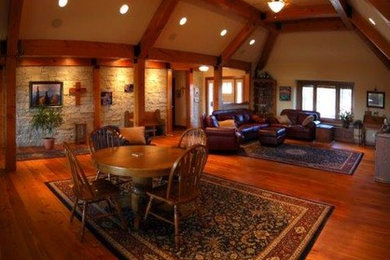 Cette image montre un grand salon chalet ouvert avec un mur beige, un sol en bois brun, une cheminée double-face, un manteau de cheminée en brique et un sol multicolore.